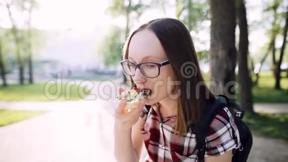 戴眼镜的白人时髦女孩吃一片带菠菜的素食披萨视频的预览图