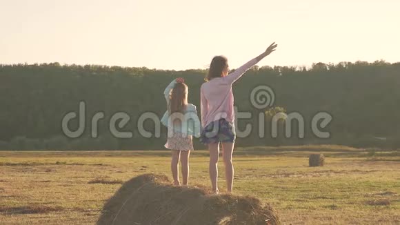 妈妈和女儿在干草堆上玩快乐的一家人在草垛上玩得开心家庭观念视频的预览图