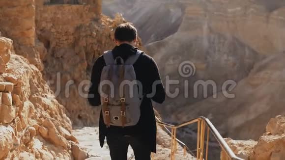 古山路上的白人男性游客拥有智能手机和相机的人享受历史沙漠以色列废墟4K视频的预览图