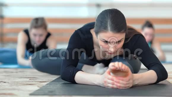 一群年轻的运动妇女在地板上做伸展运动视频的预览图