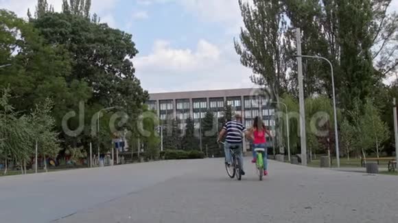 一对夫妇骑着自行车在公园里从后面石块上看视频的预览图