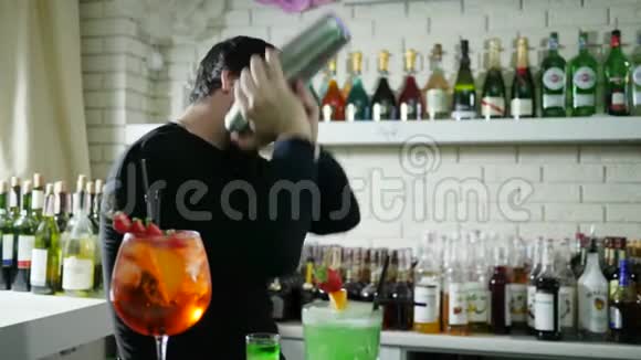 在瓶子背景下的酒吧里在摇瓶配料中混合香喷喷的视频的预览图