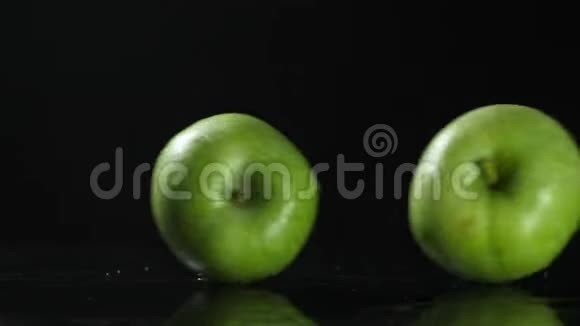 两个绿色的大苹果在两边翻滚在黑色的背景上互相撞击视频的预览图