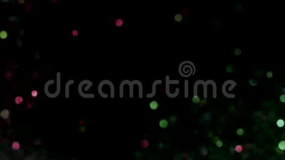 绿色和粉红色的发光闪光粒子在黑色背景上爆炸库存录像五颜六色的五彩纸屑飞舞视频的预览图