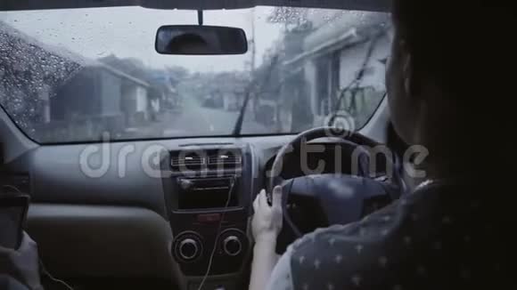 这对年轻夫妇坐在车里在雨天骑在城里的乡村道路上视频的预览图