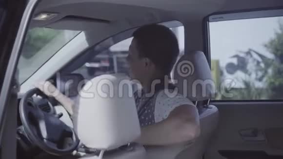 年轻的白种人坐在车里跳舞摇头转动方向盘视频的预览图