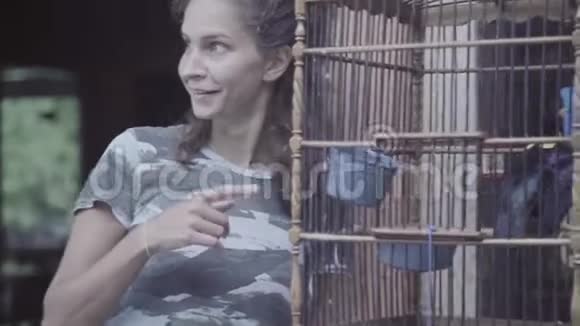 成熟的女人脸上带着惊讶的手指用大木笼和鸟视频的预览图