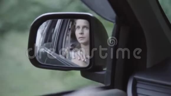 成熟的白种女人的脸映在动车的侧视镜上视频的预览图