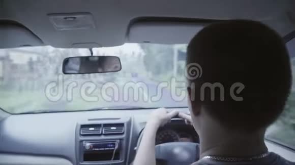 可爱的白种人摇摇头在农村路上开着右手驾驶汽车视频的预览图