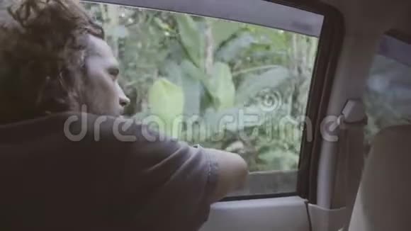两个人坐在车里而可爱的男人把头伸出窗外视频的预览图