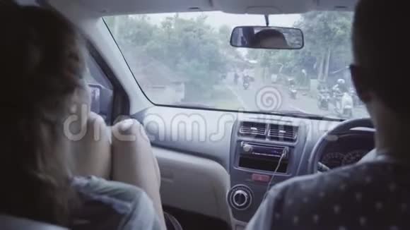 年轻的白种人男女坐在车里在东部热带地区的农村骑马视频的预览图