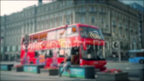 这辆红色观光巴士在市中心的城市街道上行驶模糊的图像视频的预览图