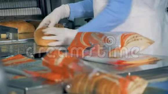 一种植物的面包包装一个女人把面包放进传送带上的塑料包装里视频的预览图