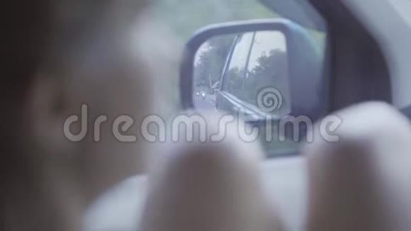年轻女子光着膝盖坐在移动的车里看着镜子的画像视频的预览图