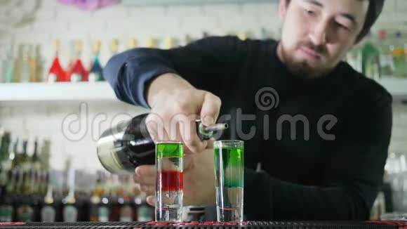 专业酒吧管理员准备彩色鸡尾酒将明亮的苏格兰威士忌从瓶子中倒入玻璃杯中并在酒吧中加入酒精视频的预览图