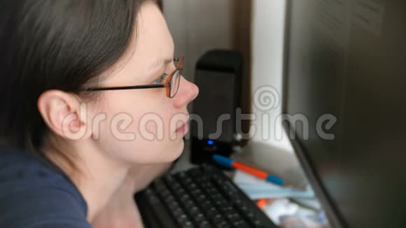 布鲁内特女士戴着眼镜在电脑屏幕上阅读文字视频的预览图