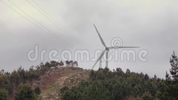 一台风力涡轮机在绿色树木之间的山上逆天旋转视频的预览图