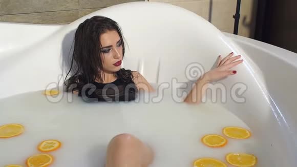 一个豪华性感的黑发女人躺在浴室里有牛奶和橘子视频的预览图