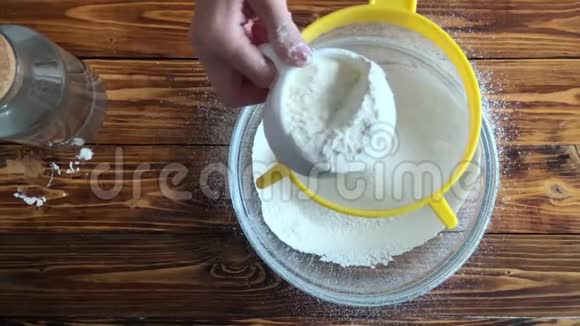 女人手拿着筛子把面粉撒进玻璃碗里做面团视频的预览图