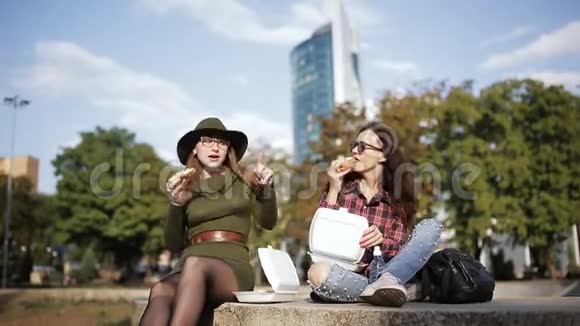 两个与众不同的女人在街上吃三明治和薯条视频的预览图