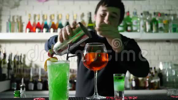 酒吧里的酒吧里酒吧里的酒吧老板用威士忌和柠檬从摇床上把冰块倒入鸡尾酒里视频的预览图