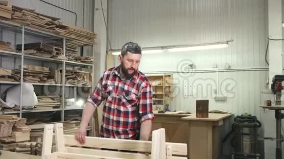 木匠在车间里穿着一件有胡子的衬衫工作做了一个木凳视频的预览图