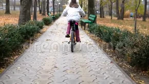 一个高加索儿童在秋季公园骑自行车公园里骑着黑色橙色自行车的小女孩视频的预览图