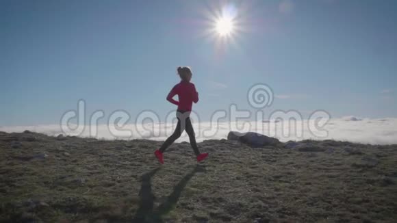 在晴朗的日子里年轻的女人在云上慢跑天空奔跑视频的预览图