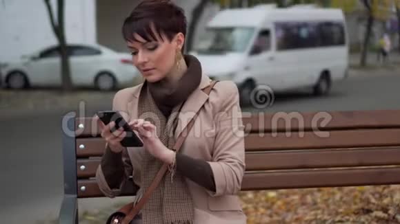年轻女性坐在长椅上使用智能手机视频的预览图