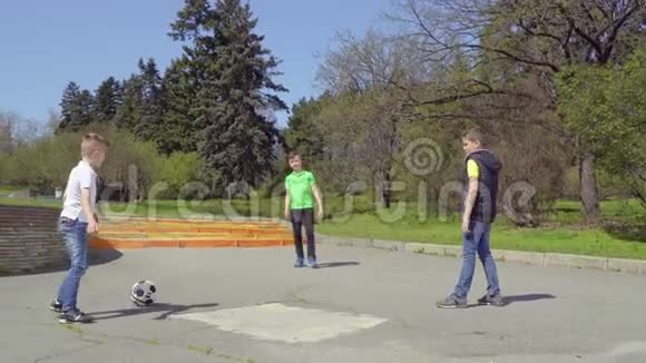 三个男孩在公园踢足球第四个男孩骑着脚踏车视频的预览图
