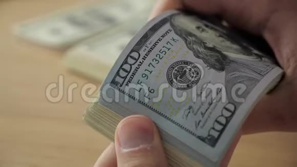 商人的手在桌子上数着一百美元的钞票视频的预览图