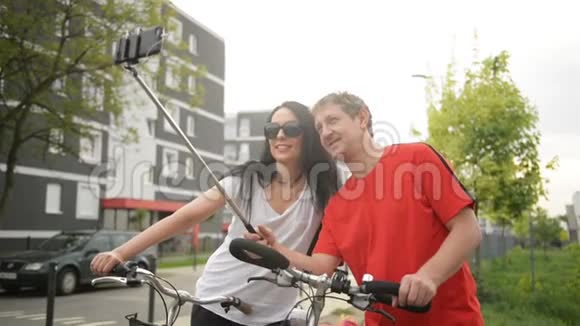 成年夫妇骑自行车后自拍一个人持有莫诺波德他们坐在自行车上视频的预览图