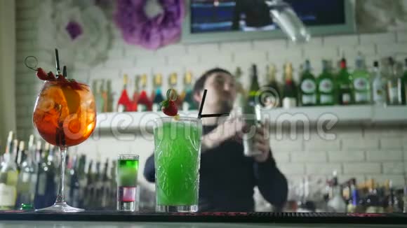 五颜六色的鸡尾酒与新鲜浆果站在酒吧柜台和不集中的背景酒保表演技巧视频的预览图