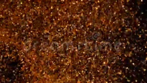 铜颗粒在水中混沌运动黄金背景金色的光芒闪耀在黑色上美丽的抽象视频的预览图