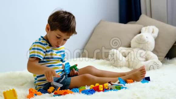 慢动作亚洲男孩玩彩色建筑塑料块在白色床上在家里视频的预览图