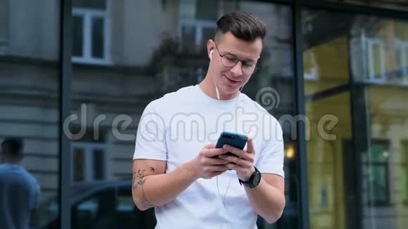 男人用智能手机在社交媒体上滚动以设备为素材从街上应用程序上的新闻中微笑视频的预览图