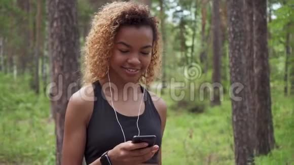 年轻漂亮的黑发女孩卷发在慢跑和看镜头后散步视频的预览图