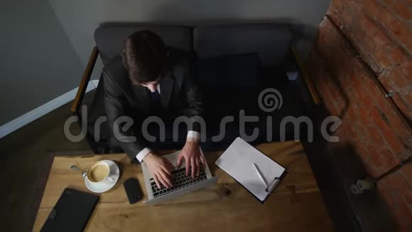商人在笔记本电脑上工作在咖啡馆里喝咖啡悲伤的商人想系上领带顶部视图视频的预览图
