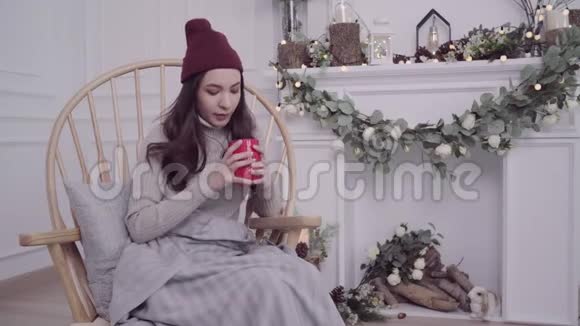 美丽迷人的亚洲女人拿着一杯温暖的咖啡或茶躺在椅子上当她在家里的客厅放松视频的预览图