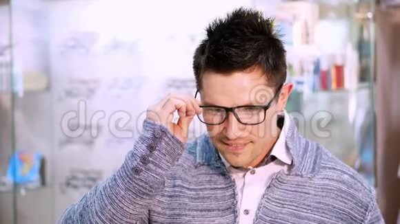 在光学商店里英俊的年轻人选择带有透明和深色太阳镜的特殊眼镜框视频的预览图