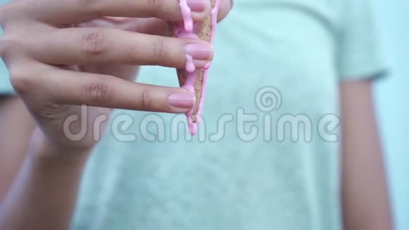 粉色融化的冰淇淋在蓝色背景下的黑色女孩手指上缓慢流动视频的预览图