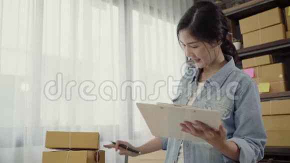 美丽聪明的亚洲青年企业家女企业家中小企业检查产品库存和写在剪贴板上工作视频的预览图