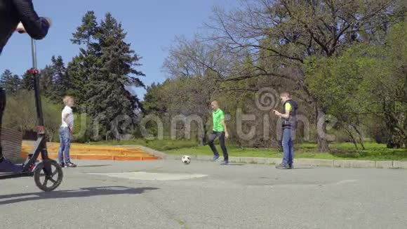 男孩们在公园里踢足球用电话和骑踢踏车视频的预览图