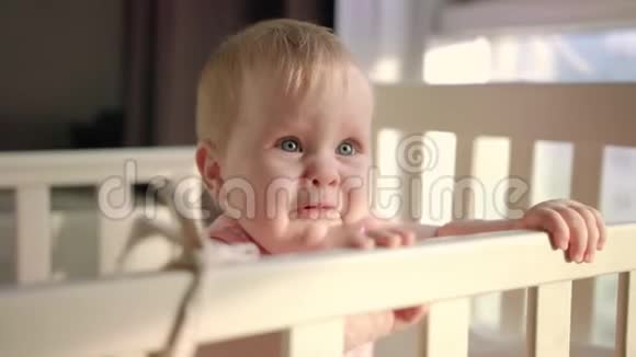 快乐的孩子站在婴儿床上微笑的蹒跚学步的孩子站在家里的床上视频的预览图