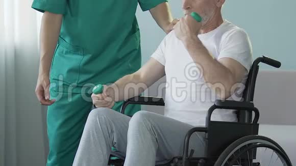 坐在轮椅上的老人举起哑铃在他身边护理外伤视频的预览图