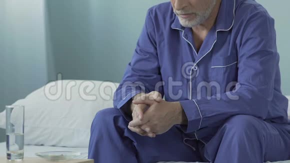 坐在床上的老人晚上的桌子上放着碗里的药丸视频的预览图