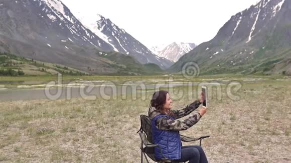 带平板电脑的女游客在视频通话在群山的背景下视频的预览图