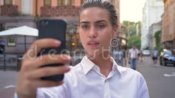年轻的现代女性站在街上在智能手机上自拍微笑沟通概念城市概念视频的预览图