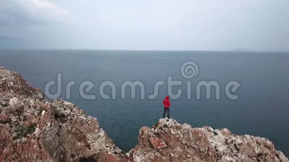 一个女孩站在海边的悬崖边上无人机的空中射击贝加尔湖视频的预览图