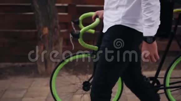 令人难以辨认的年轻商人骑着自行车在城里的街道上行走一边骑着他的自行车视频的预览图